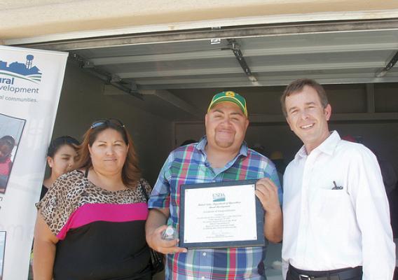 New Mexico USDA Rural Development  State Director Terry Brunner (r) presents a certificate of congratulations to Sandra and Miguel Duarte.  The presentation was made during National Homeownership Month event in Sunland Park to honor the Durate family for becoming new homeowners. USDA photo.