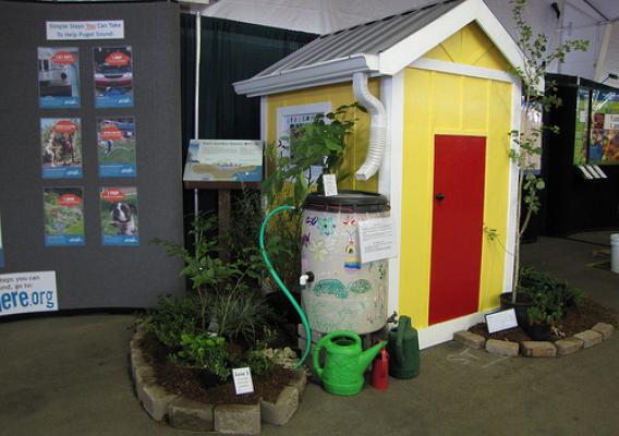 The bright yellow demonstration house built by Earth Team volunteers Mike and Jill Viafore is being used at fairs and exhibits to show how to install a home rain barrel and miniature rain garden. Using these practices, homeowners can save water and protect nearby lakes and streams from pollution. 
