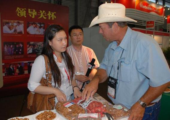 Tim Montz (right) of the Montz Pecan Company speaks with members of the Chinese media while displaying his Texas-grown products at the USDA-supported SIAL China food trade show in 2009. Participation in USDA events and export assistance from the Foreign Agricultural Service has helped international sales of Montz pecans thrive in recent years. Photo by Cindy Wise of the Texas Pecan Growers AssociationTim Montz (right) of the Montz Pecan Company speaks with members of the Chinese media while displaying his T