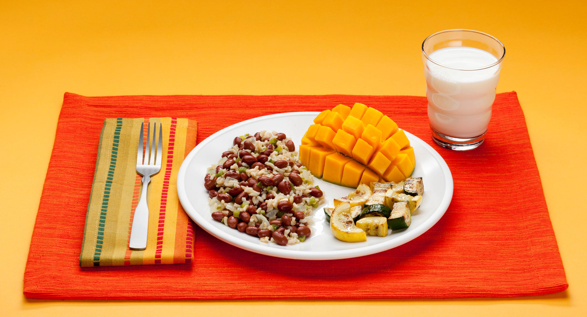 A plate of food and a glass of milk on a mat