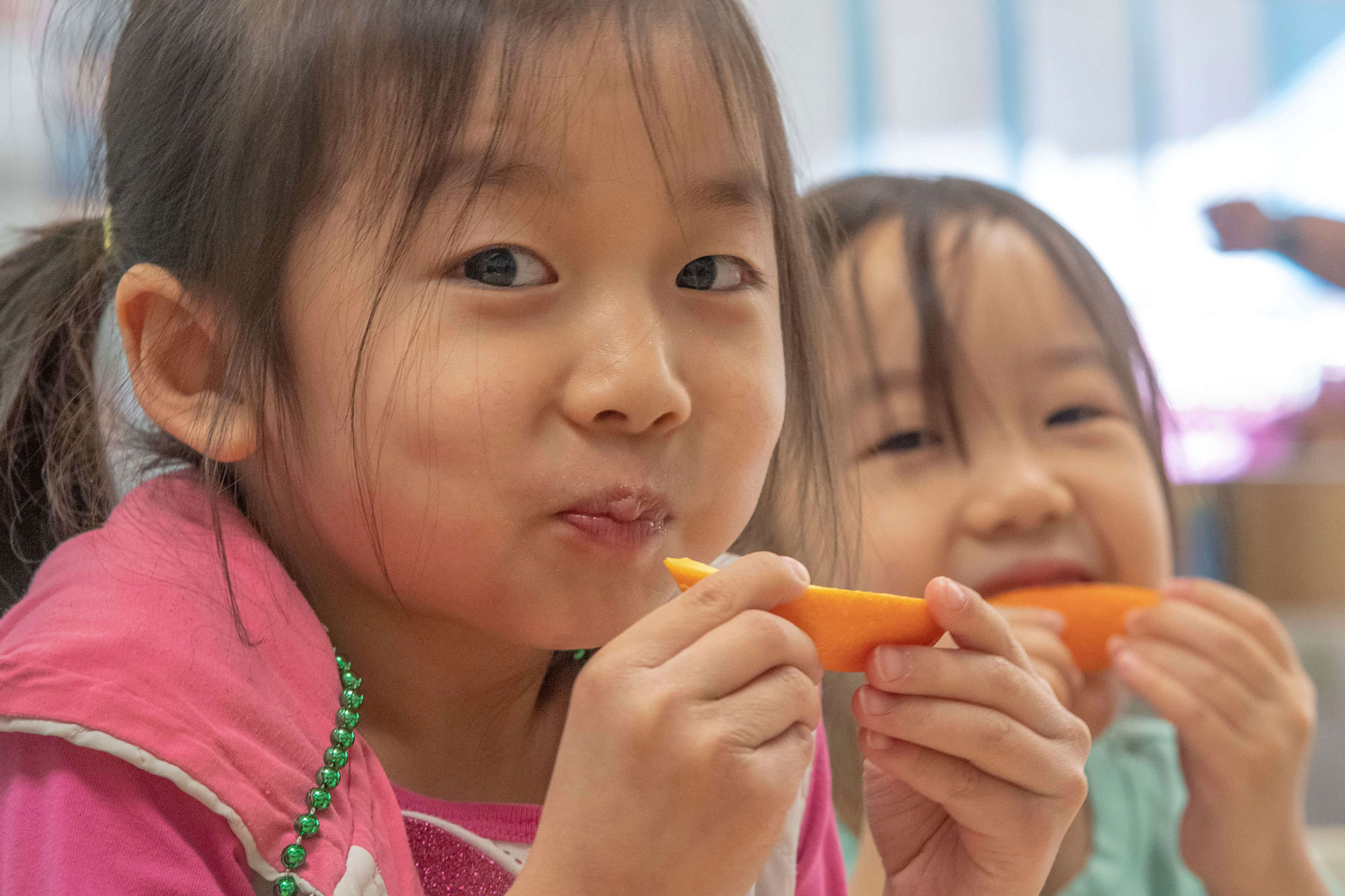 Two girls eating carrots