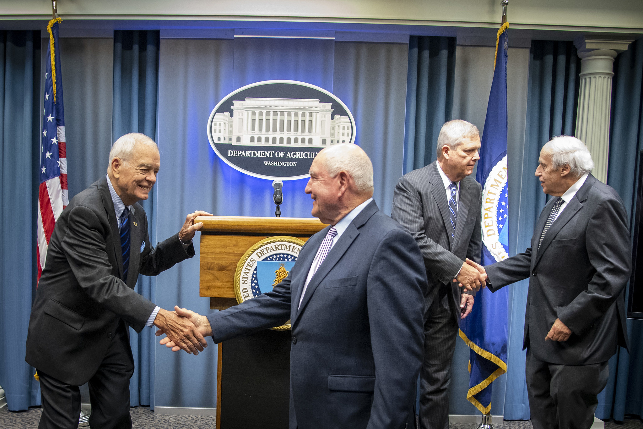 USDA Former Secretaries and Secretary Perdue shaking hands at USMCA press conference