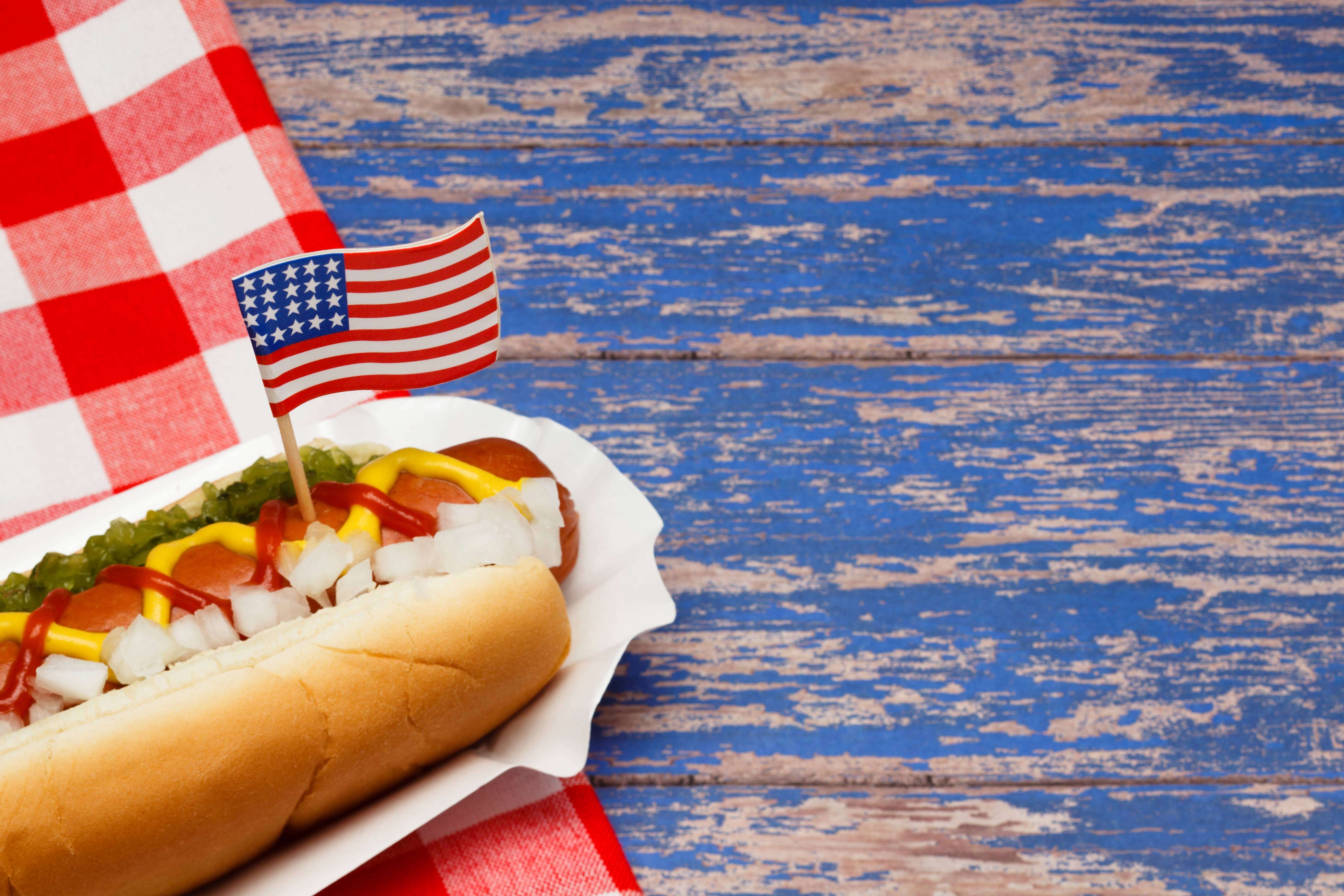 A hotdog with a US flag on top of the hotdog