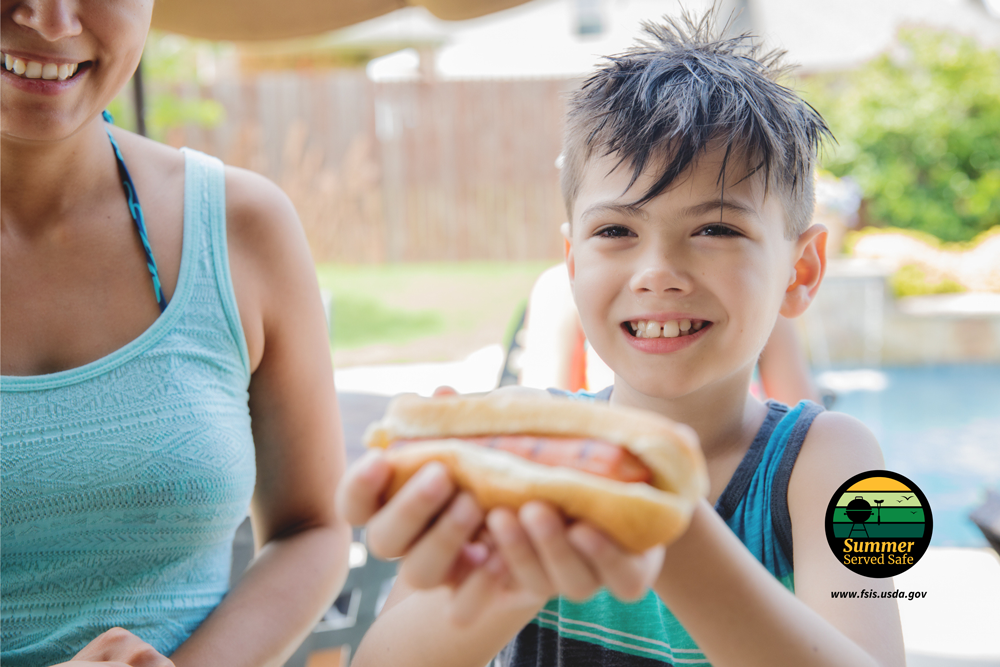 A boy getting a hot dog at the pool with a woman beside him smiling with a Summer Served Safe logo overlay