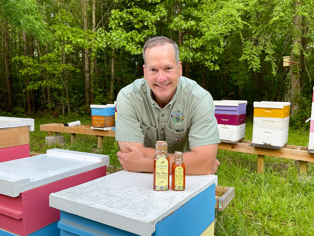 Veteran farmer Jim Hartman in front of his bottles of honey