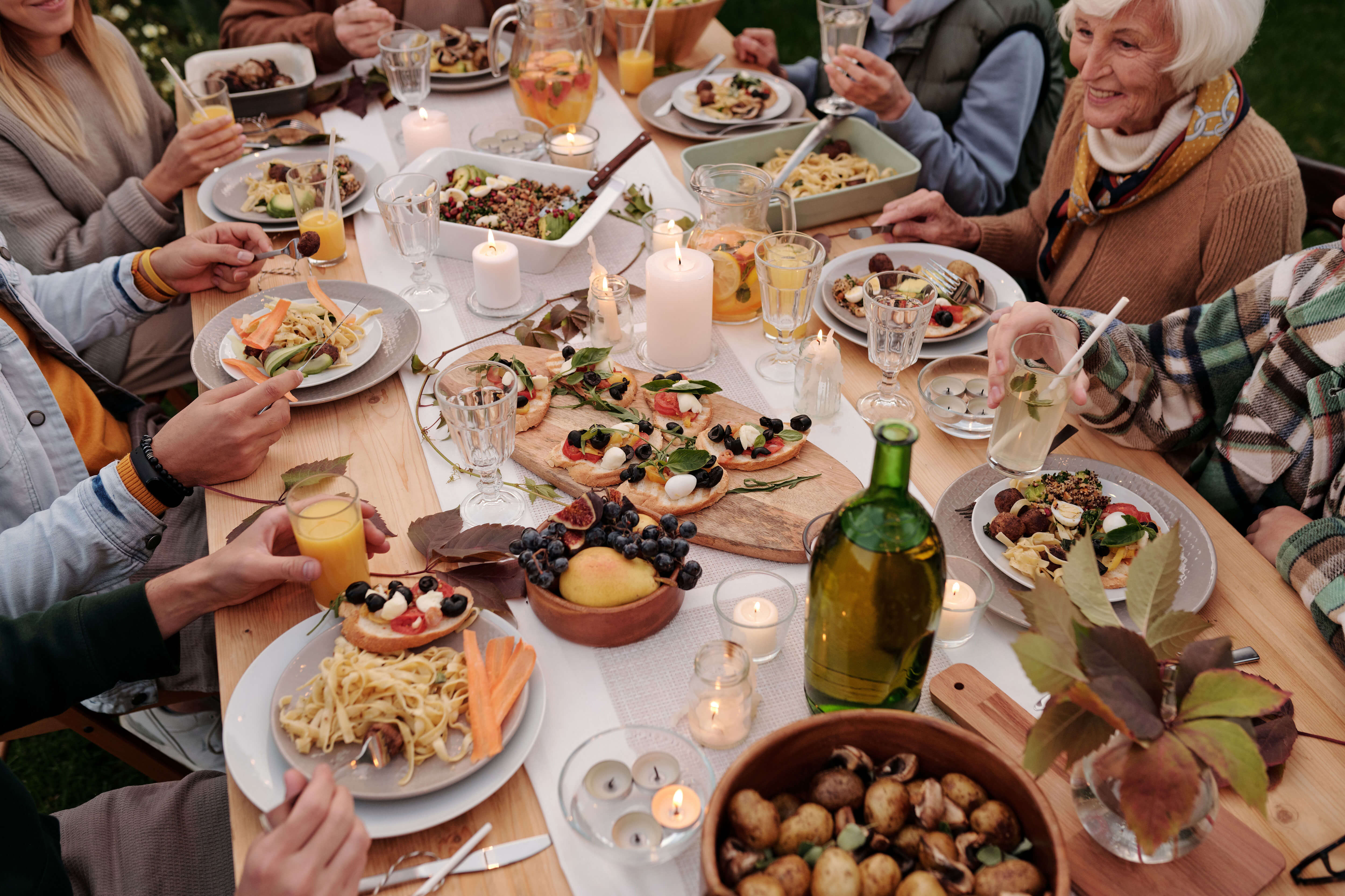 A family enjoying a meal while seated at a table covered with different foods and beverages