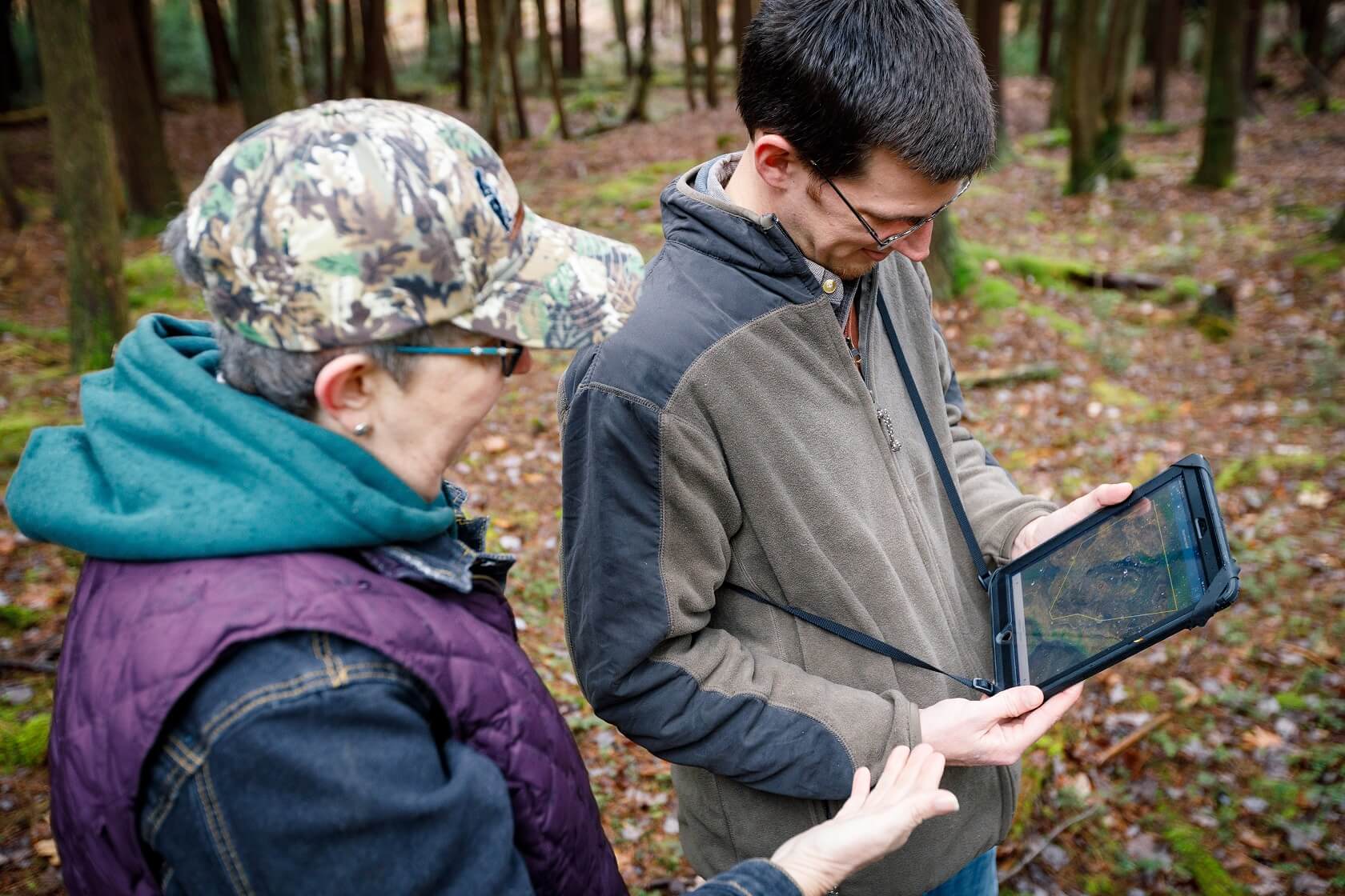 Two people looking at a laptop in a forest