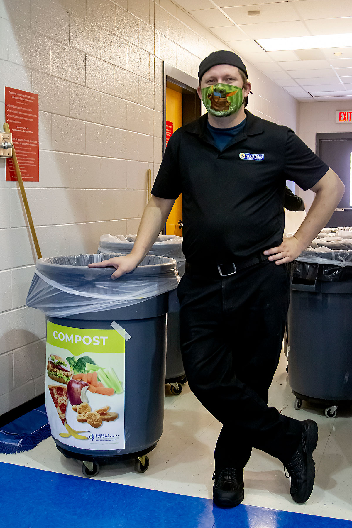 A man standing beside compost cans