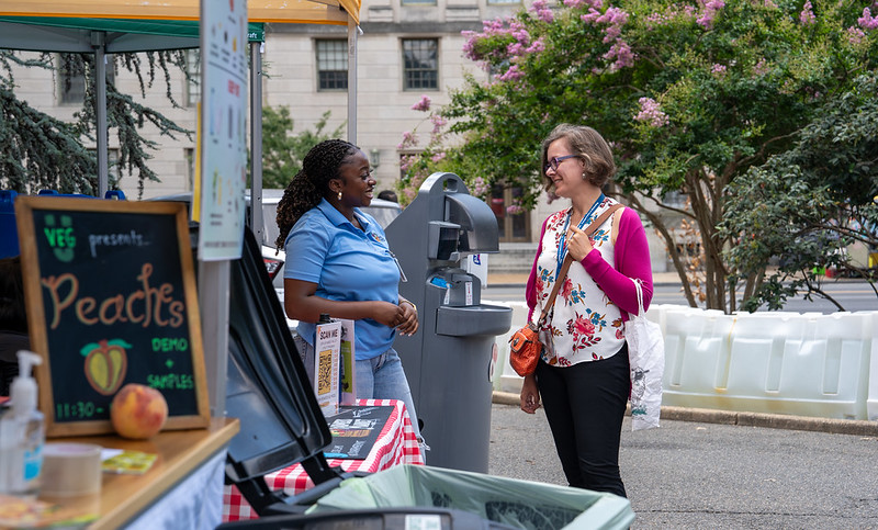 two women engage at an outdoor market