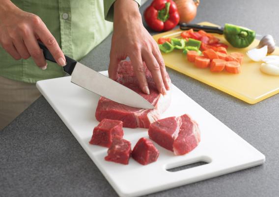 A person cutting meat and vegetables