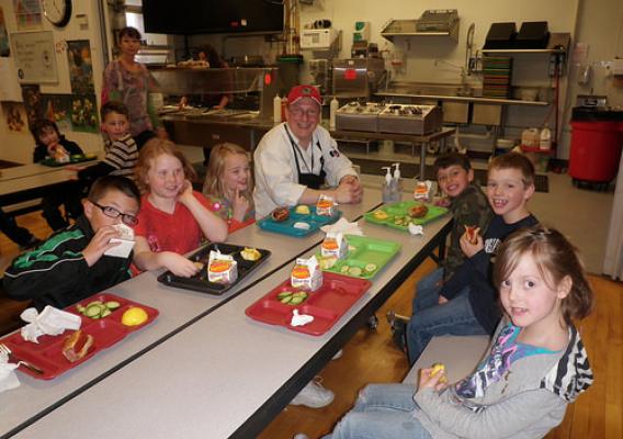 Students sitting and eating their lunch with School Chef Jason Moore