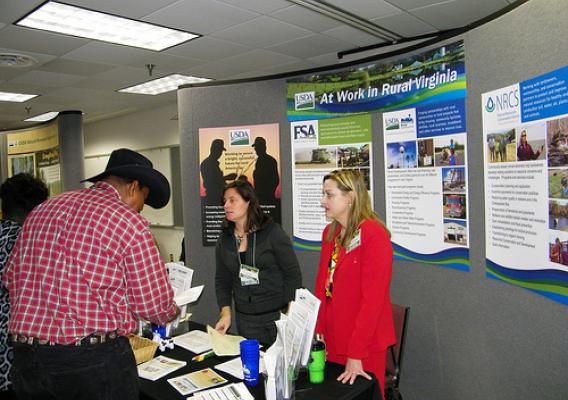 Linda Cronin (Left), Public Affairs Specialist for FSA and Janice Stroud-Bickes (Right) Area Director for Rural Development are reviewing USDA program details with local producer at the USDA information booth