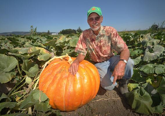 Farmer David Brown poses next to one of his giant pumpkins. Healthy soil is key to the success of Mustard Seed Farms. Photo courtesy of NRCS.