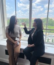 Two women speaking near a window